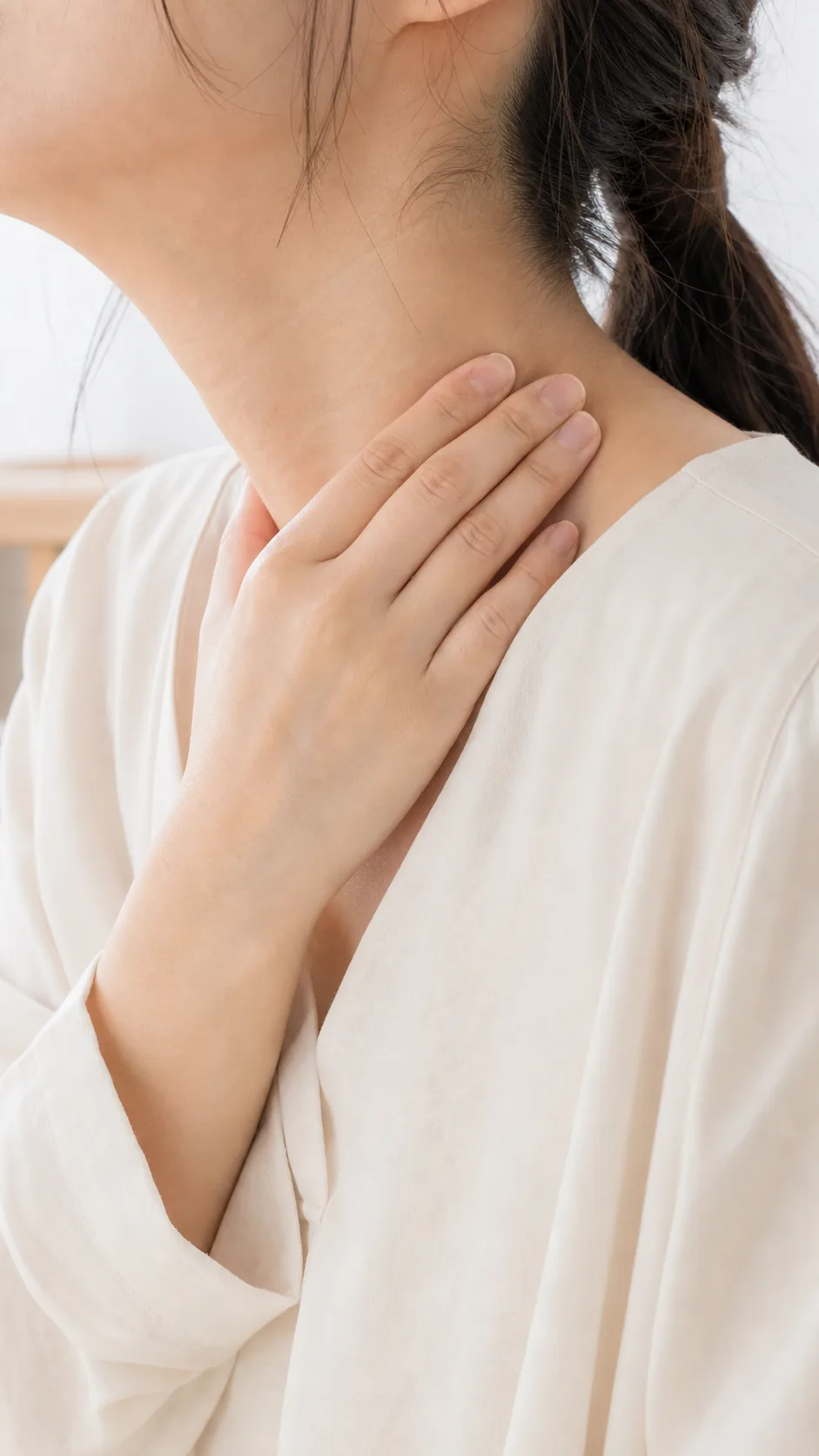 首から肩にかけてのこりを手で押さえる女性のクローズアップ（イメージ画像）